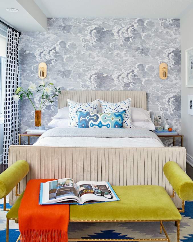 cloud wall mural and velvet headboard and velvet bench at end of bed