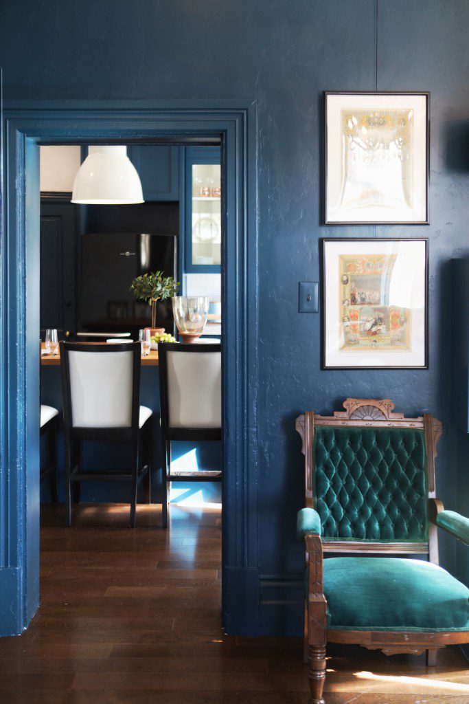 navy blue kitchen with oversized pendants and green velvet chair