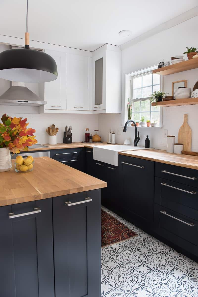 patterned tiled floor in kitchen with black cabinets, butcher block counters, and open shelving