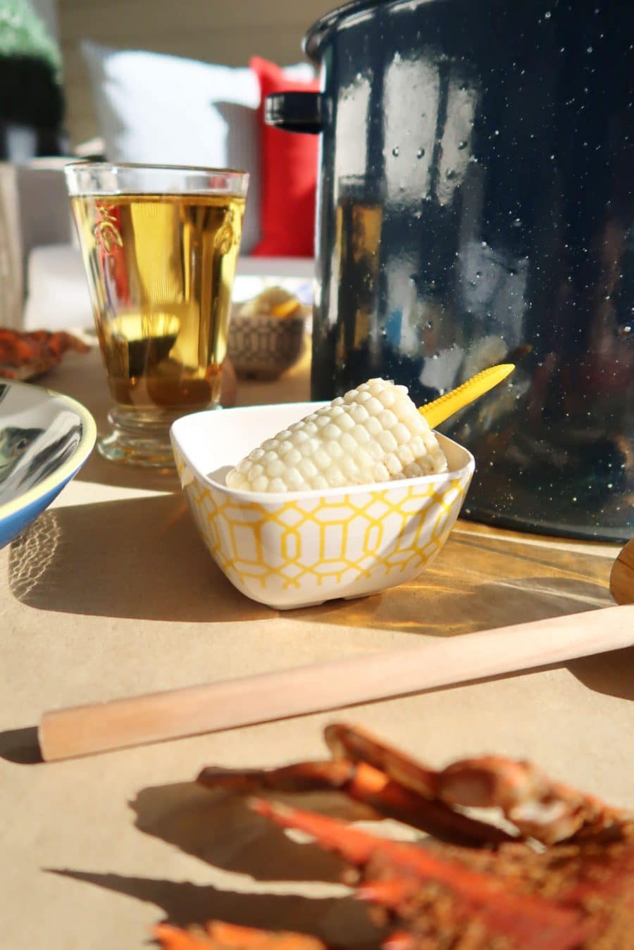 close up of corn in a dish and blue stock pot, beer at a crab feast on patio