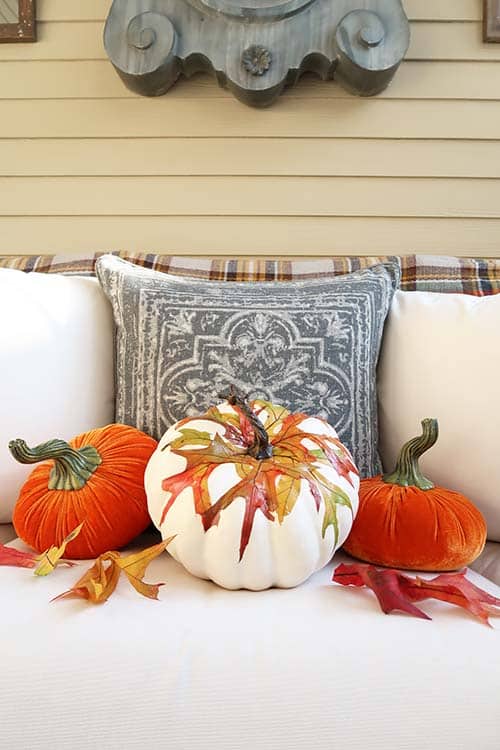 fall leaves applied to white pumkin on white sofa with two orange velvet pumpkins