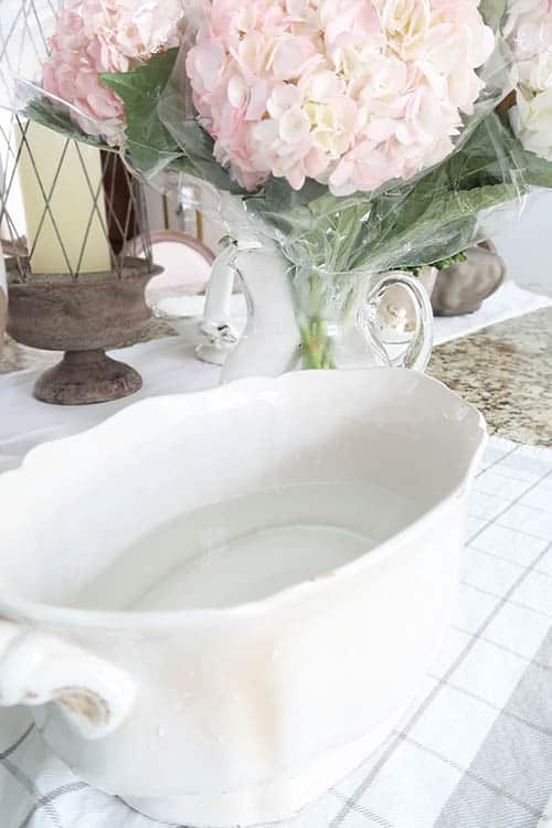 off white planter filled with water pink hydrangeas in pitcher