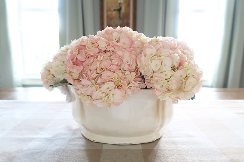 pink hydrangeas in a cream ceramic planter on dining room table
