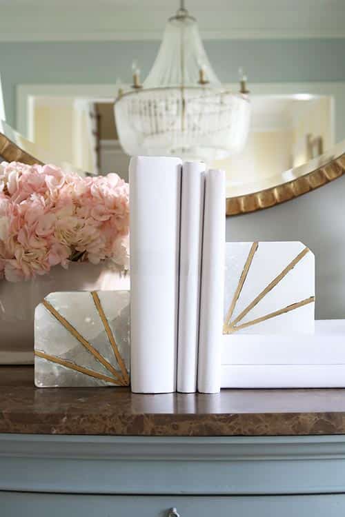 vertical books wrapped in white craft paper with pink hydrangeas and white lamps