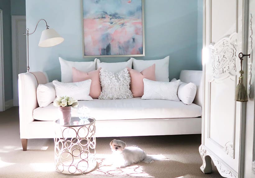 white daybed in blue room with blush pillows and white maltese