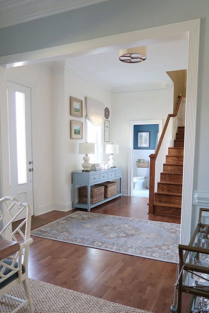 foyer-in-white-with-pottery-barn-finn-rug-blue-console-looking-into-powder-room