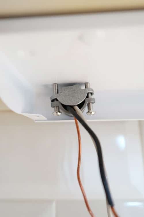 LED-light-fixture-attached-under-cabinet-with-wires-pulled-through-strain-relief