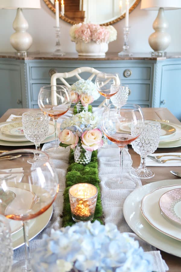 close-shot-down-romantic-vintage-table-with-blue-hydrangeas-pink-roses-moss-table-runner-pink-wine-glasses
