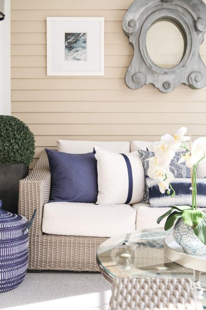 layers-of-textures-glass-round-table-orchid-blue-white-planter-round-topiary-bush-black-planter-silver-woven-rug-white-navy-pillows-min