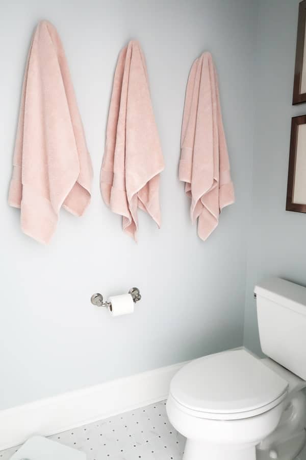 three-blush-pink-towels-hanging-on-rob-hooks-toilet-room