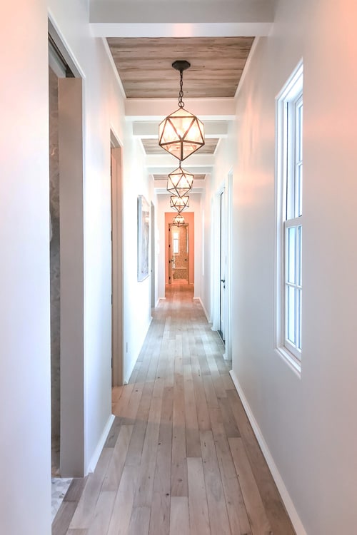 long-hall-way-with-bleach-pine-floors-and-geometric-pendant-lights