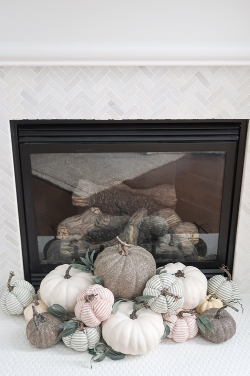 close-up-of-various-pumpkins-stacked-in-front-of-fireplace