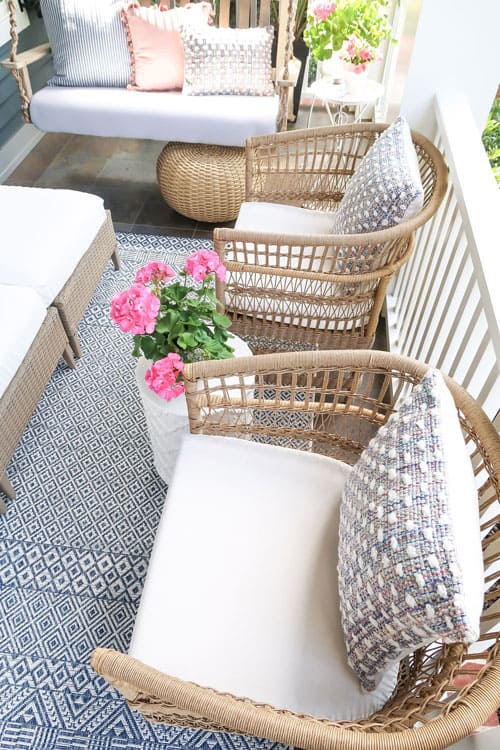 woven-barrel-chairs-against-railing-blue-white-rug-pillows-pink-geraniums_4