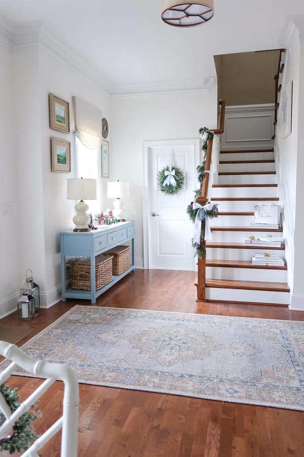looking-into-foyer-finn-rug-packages-on-stairs-garland-on-banister-wreath-on-door