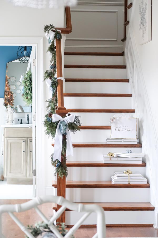 stair-banister-decorated-with-garland-and-white-bows-christmas-packages-on-stairs-view-of-power-room